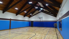 Un terrain de basket-ball intérieur doté d’un plancher en bois, de murs bleus et d’un panier de basket.
