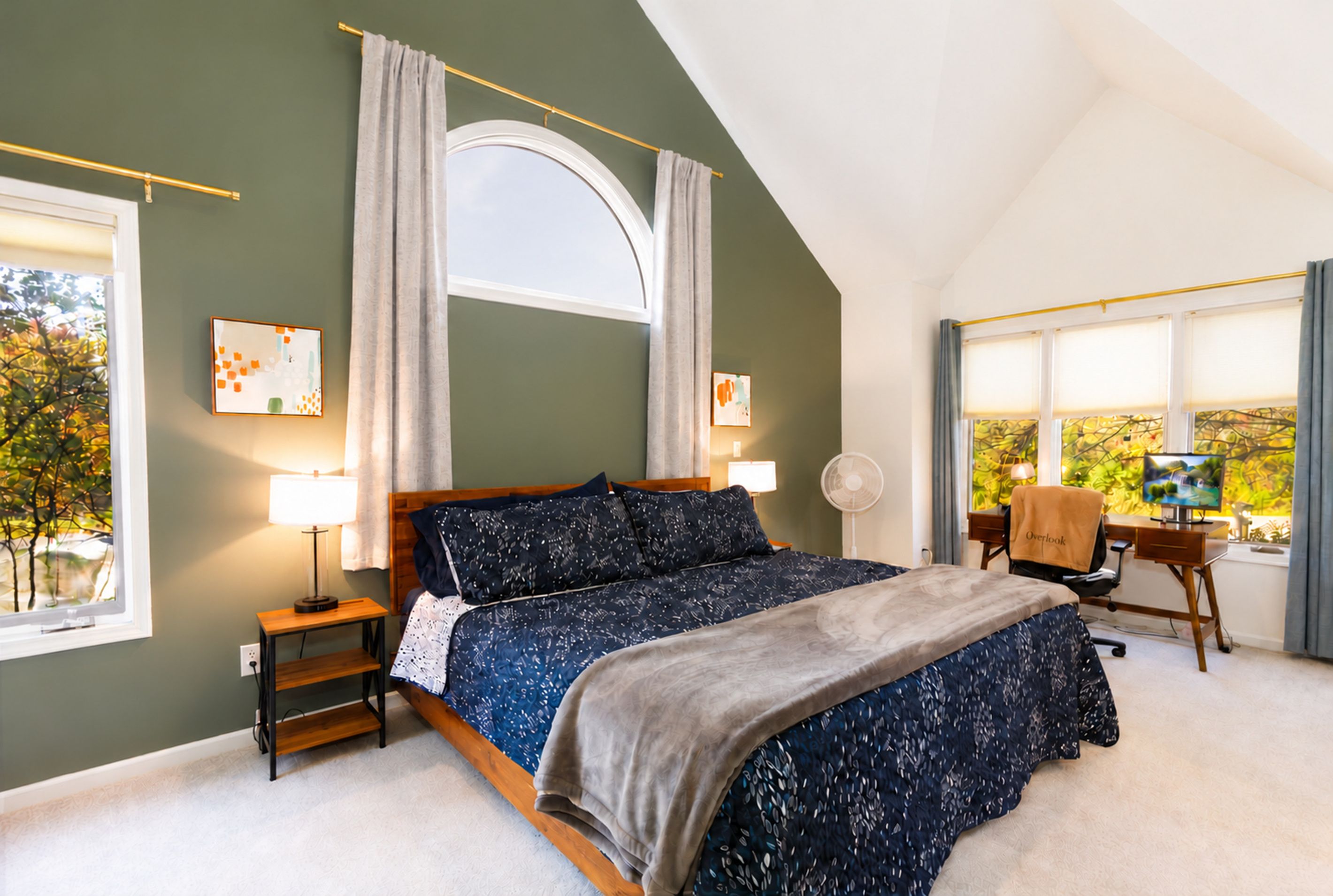 Une chambre à coucher avec un lit, un bureau, une chaise, une fenêtre et des œuvres d’art accrochées aux murs.