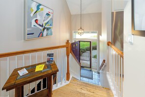 A staircase with a wooden handrail, a bench with a 'Guest Pass' sign, and a painting on the wall.