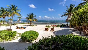 Een strand met palmbomen, ligstoelen en een helder uitzicht op de oceaan.