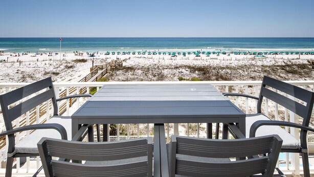 Ein Tisch mit Stühlen am Strand mit Blick auf einen Sandstrand und den Ozean.