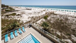 Ein Poolbereich mit Liegestühlen und Blick auf Strand und Meer.