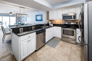 A modern kitchen with white cabinets, stainless steel appliances, and a black granite countertop.