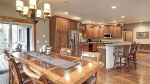 A spacious kitchen with wooden cabinets, a large island, and a dining area with a chandelier. - Turkey Ridge Lodge - just outside of Deadwood! (Sturgis)