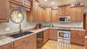 A kitchen with wooden cabinets, a stainless steel oven, a microwave, and a granite countertop. - Turkey Ridge Lodge - just outside of Deadwood! (Sturgis)