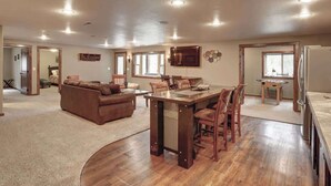 A spacious living area with a wooden dining table, a brown sofa, and a kitchen area with a refrigerator and a microwave. - Turkey Ridge Lodge - just outside of Deadwood! (Sturgis)