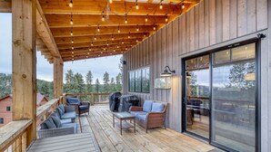 A covered outdoor deck with wooden flooring, a sofa, chairs, and a barbecue grill. - Happy Hour Hideaway - Mountaintop views! (Lead)