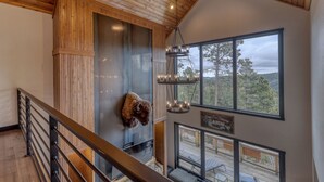 A high-ceilinged room with wooden beams, a mounted bison head, and a view of the outdoors through large windows. - Happy Hour Hideaway - Mountaintop views! (Lead)