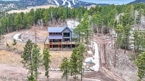 A modern two-story cabin surrounded by dense forest, with a dirt road leading to it. - Happy Hour Hideaway - Mountaintop views! (Lead)
