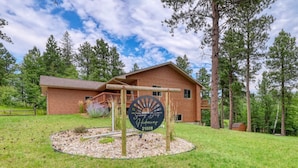 A wooden lodge with a circular driveway and a sign indicating 'Sunny Bay Hideaway 21009'. - Sunny Day Hideaway - Private! Firepit and Hot tub! (Sturgis)