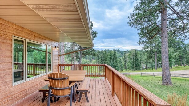 A wooden deck with a table and chairs, overlooking a forested area. - Sunny Day Hideaway - Private! Firepit and Hot tub! (Sturgis)