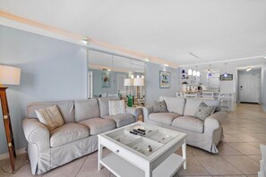 A living room with two sofas, a coffee table, and a dining area with chairs and a table.