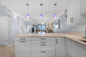 A kitchen with white cabinets, a central island, and pendant lighting.