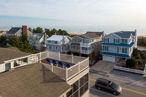 Un barrio residencial con casas, un balcón con sillas azules y vista a la playa.