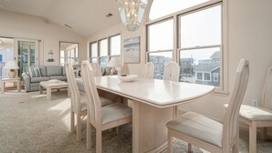 Un salon spacieux avec une grande table à manger, des sièges confortables et de grandes fenêtres offrant une vue sur la ville.