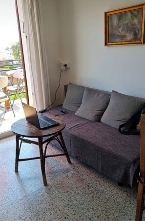 Ein Wohnbereich mit einer Couch, einem runden Tisch und einem Laptop.