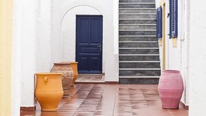 A corridor with terracotta pots, a blue door, and a staircase. - Elia (Patmos)