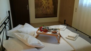 Ein ordentlich gemachtes Bett mit weißen Leinentüchern, ein Tablett mit Tee, Keksen und einem Blumenstrauß.