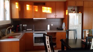 Eine kleine Küche mit Holzschränken, einem Edelstahlspülbecken, einem Einbauofen und einem Kühlschrank.