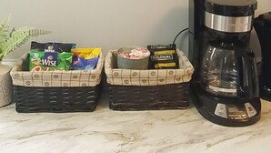 Una cafetera, dos cestas de cápsulas de café y un letrero que dice '¿CAFÉ, ALGUIEN?'