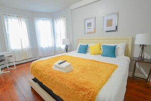 Une chambre d’hôtel avec un grand lit, un bureau et deux fenêtres équipées de rideaux.