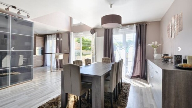 A modern kitchen with a dining area, large windows, and a view of greenery outside. - House 120 m² in Vigy (Vigy)