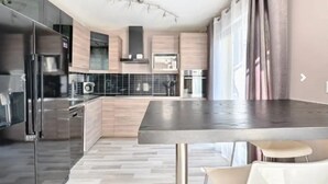 A modern kitchen with a large island, stainless steel appliances, and light wood cabinetry. - House 120 m² in Vigy (Vigy)