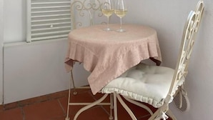 A small room with a round table, a chair, a window with shutters, and a wall-mounted light switch. - moon (Monopoli)