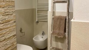 A bathroom with a bidet, toilet, and a wooden ladder leaning against the wall. - moon (Monopoli)