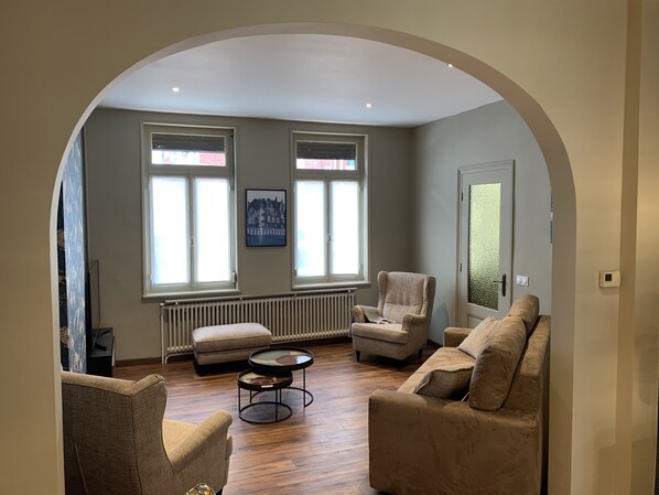 Un salon comprenant un canapé, des fauteuils, une table basse et un radiateur.