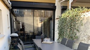 An outdoor patio with a table and chairs, a bottle, and glasses.