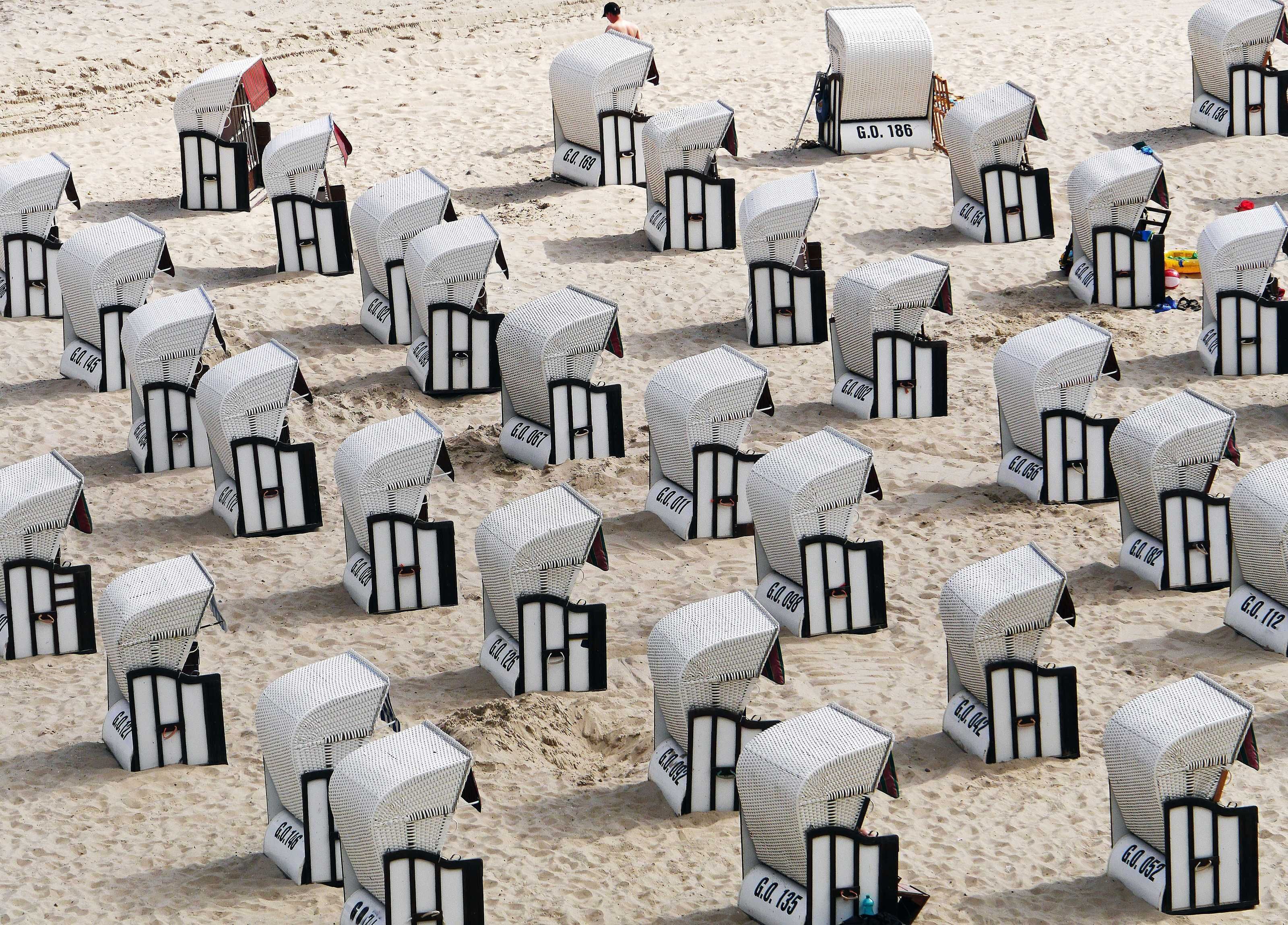 A beach with numerous white beach chairs labeled with numbers, arranged in rows.