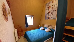 Ein Schlafzimmer mit einem Bett, einem Fenster, einem Gemälde und einem Stockbett.