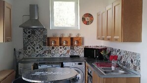 A compact kitchen with a central island, wooden cabinets, a built-in oven, and a microwave. - Barn converted into gîte for 4/5 people (audon)