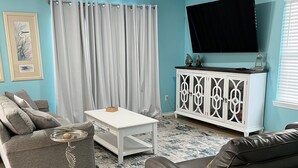 Un salon avec un canapé, une table basse et un téléviseur.