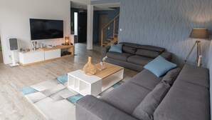 Una sala moderna con un sofá gris, una mesa de centro blanca y un televisor de pantalla plana.