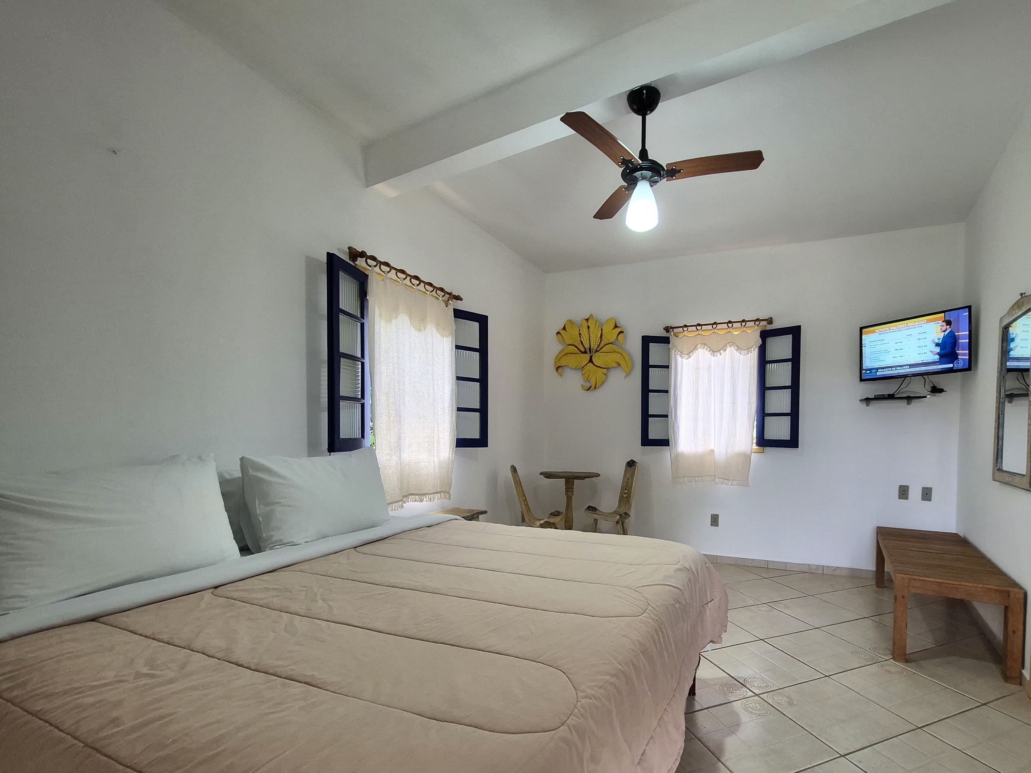 Une chambre à coucher avec un lit, un ventilateur de plafond, une télévision et une petite table.