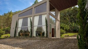 A modern building with large windows and a covered outdoor area. - Pousada Recanto das Araras (Tiradentes)