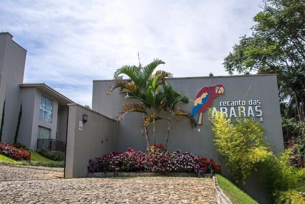 A building with a sign that reads "retalho das ARAS" and a colorful parrot illustration. - Pousada Recanto das Araras (Tiradentes)