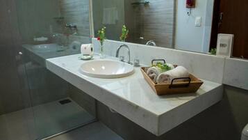 Une salle de bain moderne avec un grand miroir, un lavabo et un panier en bois contenant des serviettes.