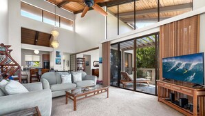 A spacious living room with a large flat-screen TV, a wooden coffee table, and a grey sofa. - KKSR#2304 DIRECT OCEANFRONT, INCREDIBLE TOP FLOOR CORNER UNIT, HUGE LANAI! (Kailua Kona)