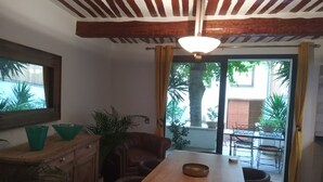 Ein Essbereich mit Holztisch und Stühlen, einem Deckenventilator und Blick ins Freie durch eine Glastür.