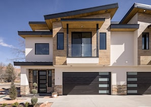 A modern two-story house with a garage, large windows, and a stone facade. - Downtown Moab | Steps from Bike Path & Restaurants (Moab)