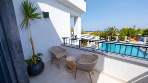A balcony with wicker chairs, a small round table, and a potted plant. - Club Kavala Beach Hotel Assos (Ayvacik)