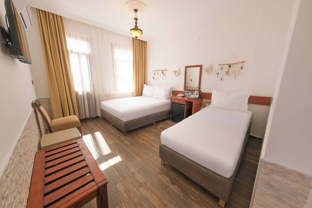 Une chambre d’hôtel avec deux lits, un bureau, une chaise et un téléviseur.