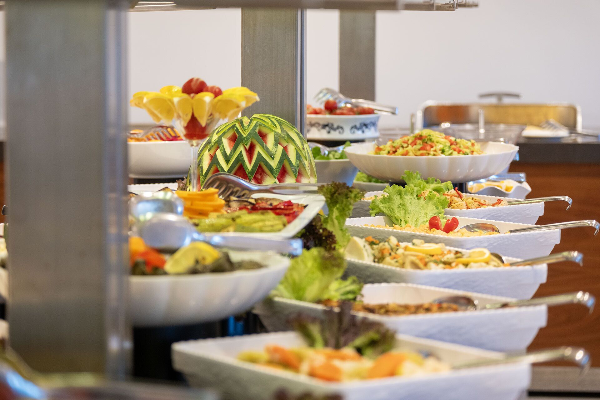 Ein Buffet mit verschiedenen Speisen, darunter Salate, Früchte und Gemüse.