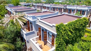 A modern hotel with multiple units, each featuring a balcony and a view of the surrounding greenery. - Club Kavala Beach Hotel Assos (Ayvacik)