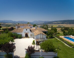 A large villa with a spacious driveway, a swimming pool, and a view of distant mountains. - Generous luxury estate with 360° views and a spacious pool (Arriate)