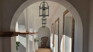 A corridor with white walls, a tiled floor, and a hanging lantern.