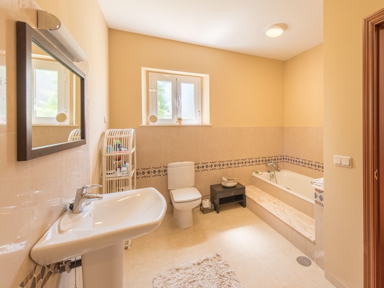 A bathroom with a sink, toilet, bathtub, and a window above the toilet.